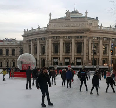 People ice skating on a rink outside.