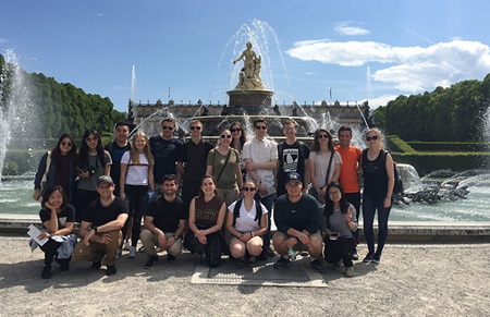 Group photo of students on a study abroad trip in Germany standing in front of a sculpture fountain.