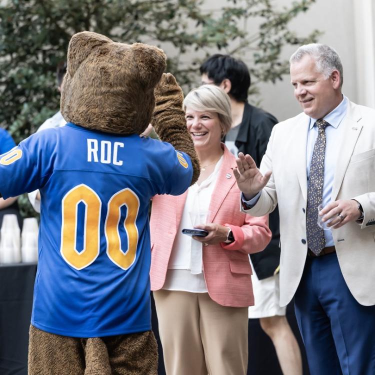 Roc the Pitt Panther mascot high fives guests at an event.
